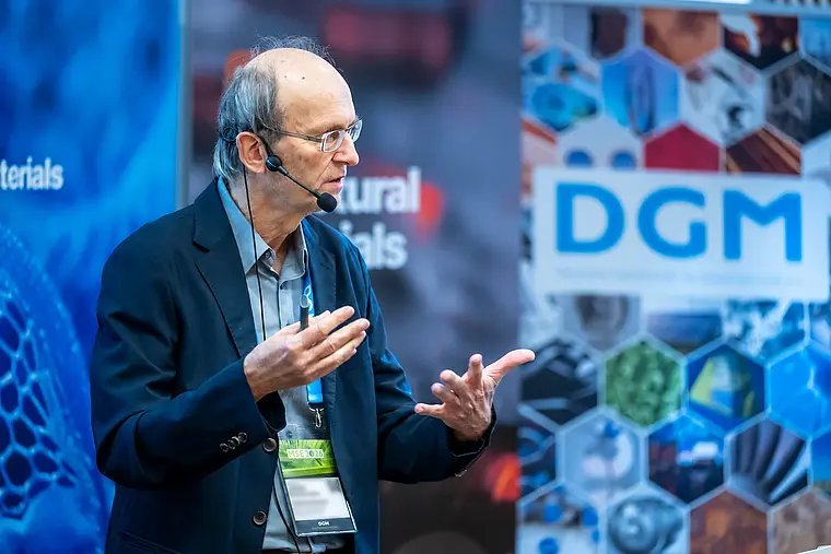 A speaker wearing a headset explains his research topic on stage