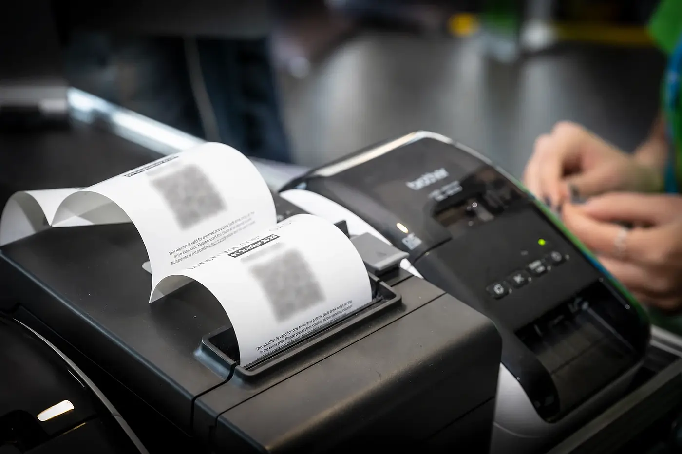 Booked vouchers/tokens are printed directly at the station; names and personal codes are obscured