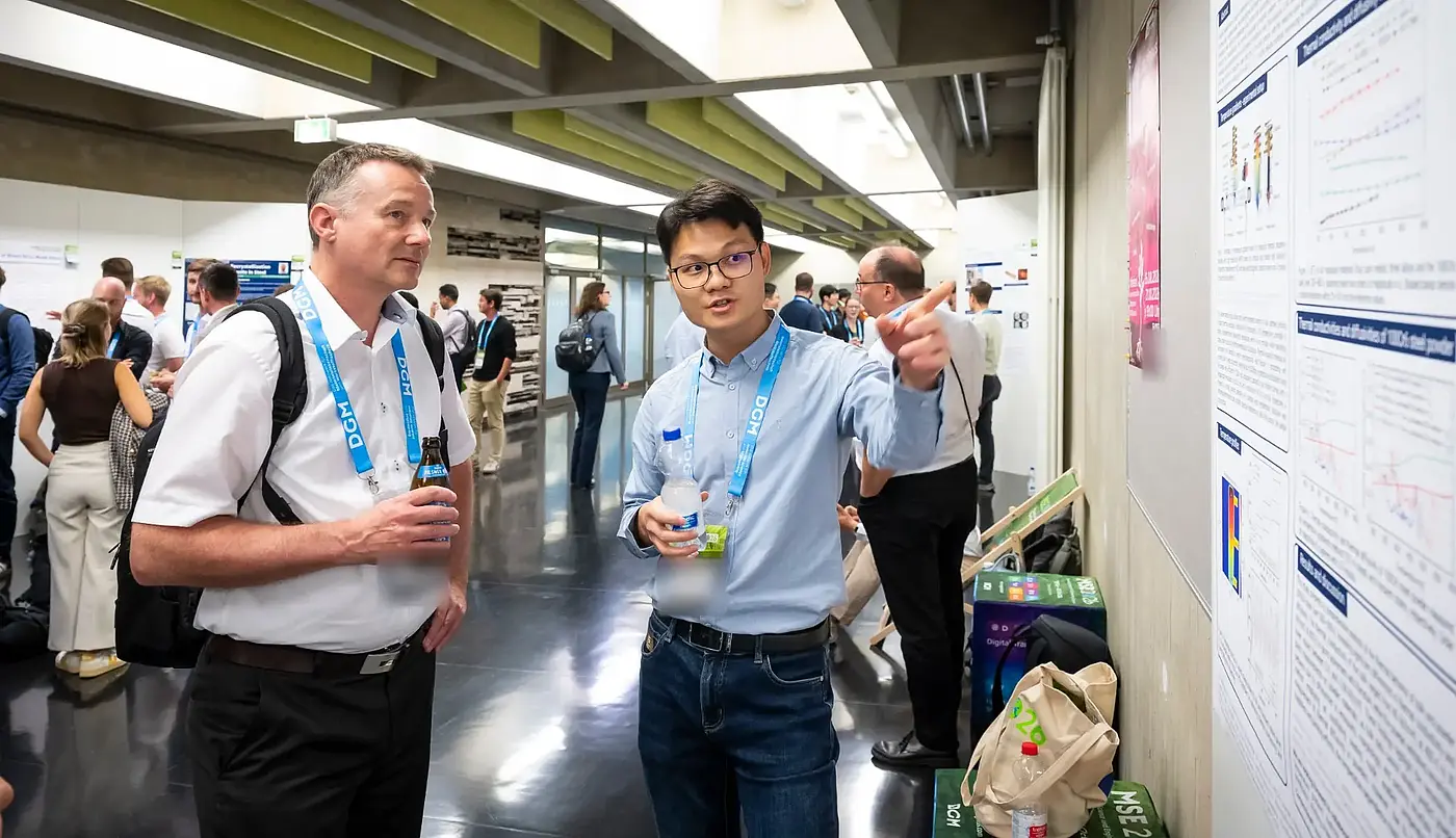 A doctoral researcher explains his poster to a conference guest