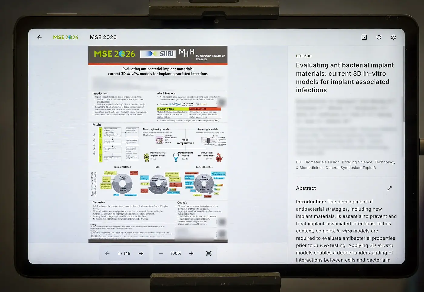 A tablet shows a scientific poster with its abstract, authors and session