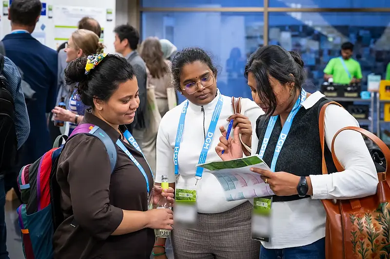 Three female participants looking at the conference program together