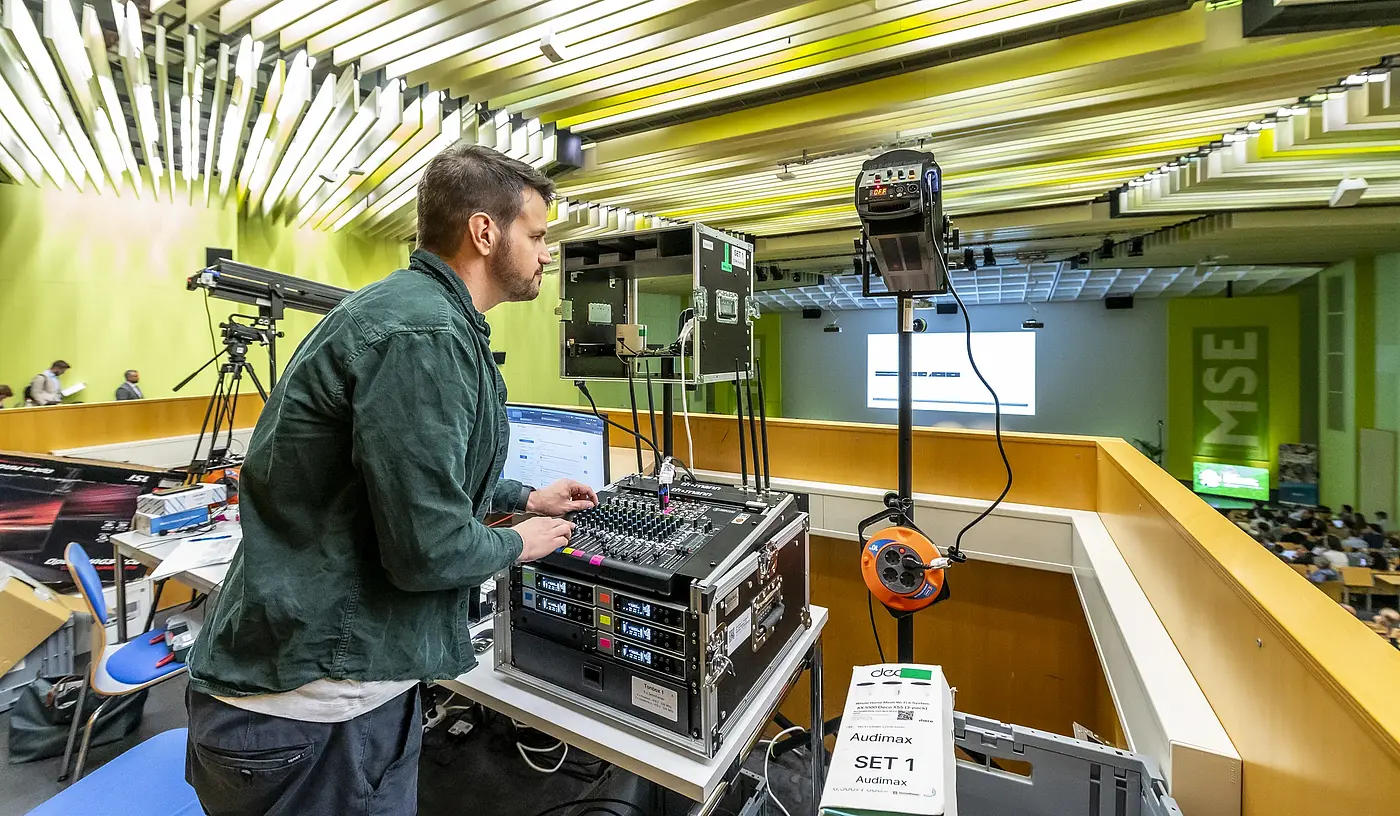 A technician with a control computer, mixing desk and camera equipment in the lecture hall