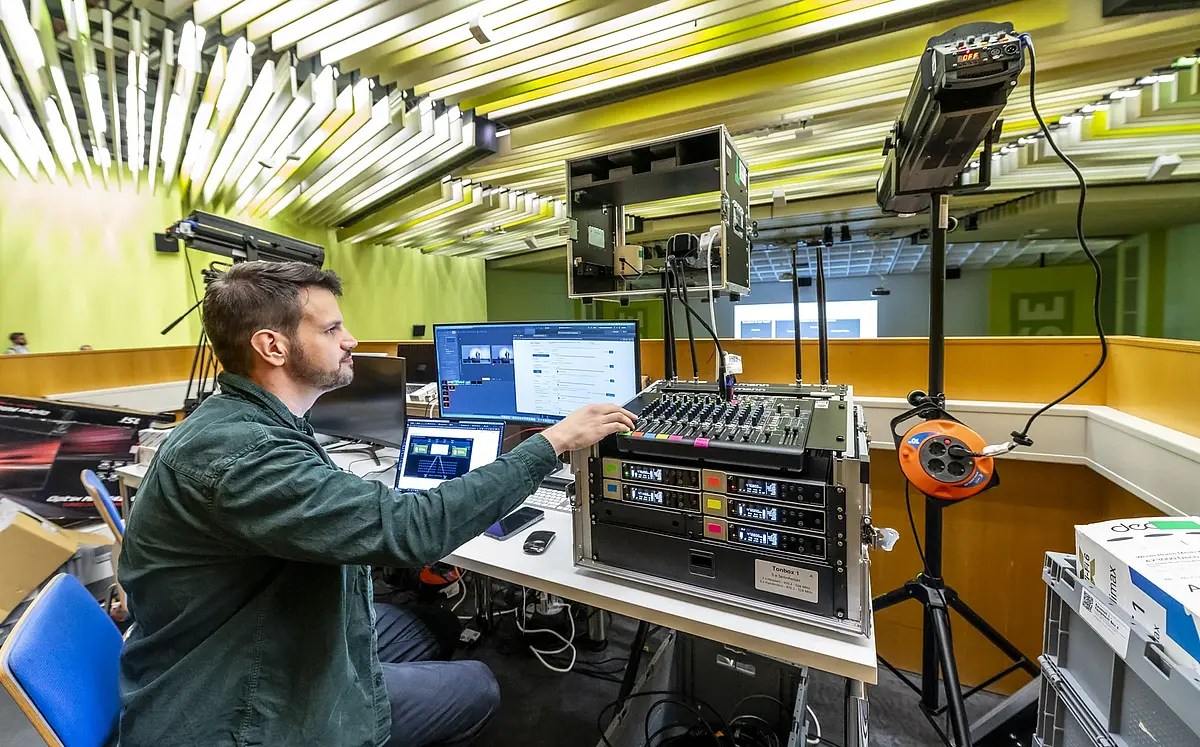 A technician manages video and audio at the control desk in the lecture hall
