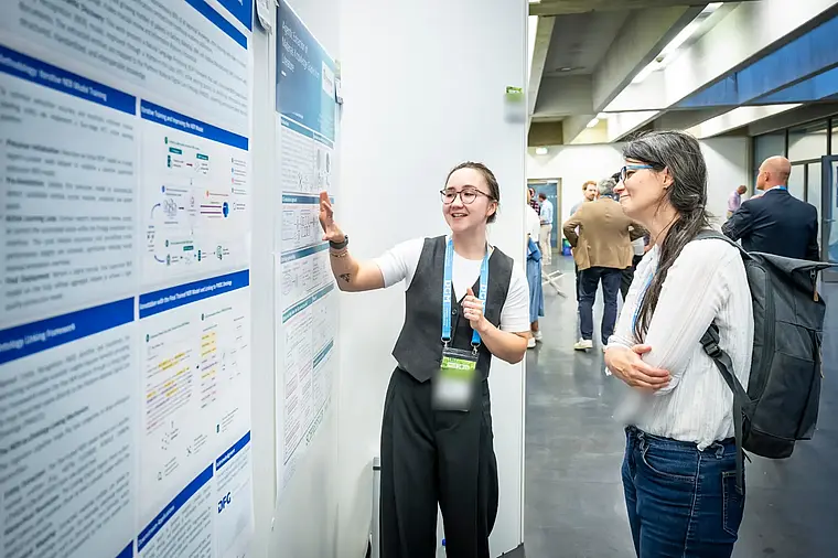 A researcher laughs while explaining her poster